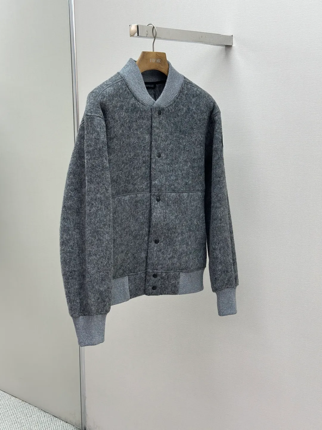 P770 Canada Goose Fleece Badge Button Jacket Fabric selection: Wool blend fabric: The main fabric of this jacket is light gray wool blend fabric to improve the fabric's wear resistance, wrinkle resistance and warmth. Wool provides good warmth and a natural feel, while blended fibers enhance the fabric's practicality and durability.  RIBBED KNIT: The collar, cuffs and hem are ribbed knitted for added stretch and fit.  Production process: The cutting process needs to ensure that the texture and color of the fabric are evenly distributed, especially for this light gray tone, to avoid color differences. The stretchability of wool-blend fabrics needs to be taken into consideration when cutting pieces to ensure dimensional stability of the finished garment.      • Use a sewing needle and thread suitable for wool-blend fabrics to avoid damage to the fabric during sewing. The sewing stitches are even and firm to prevent thread stripping.      • The temperature needs to be controlled during ironing to avoid high temperature damage to the fabric while keeping the fabric smooth and crisp.  Main body splicing: • The front and back body parts, sleeves and other main parts are spliced ​​with flat seams to ensure a smooth silhouette. •Align the fabric texture at the splicing points to keep the appearance neat.     Details such as pockets and cuffs are designed with inset pockets to increase practicality and aesthetics.     The splicing areas are reinforced to improve durability.  Armband: The white round armband on the left arm is an important part of the brand identity and is finely sewn to ensure it is strong and flat.  Dark gray and light gray Size: S M L XL